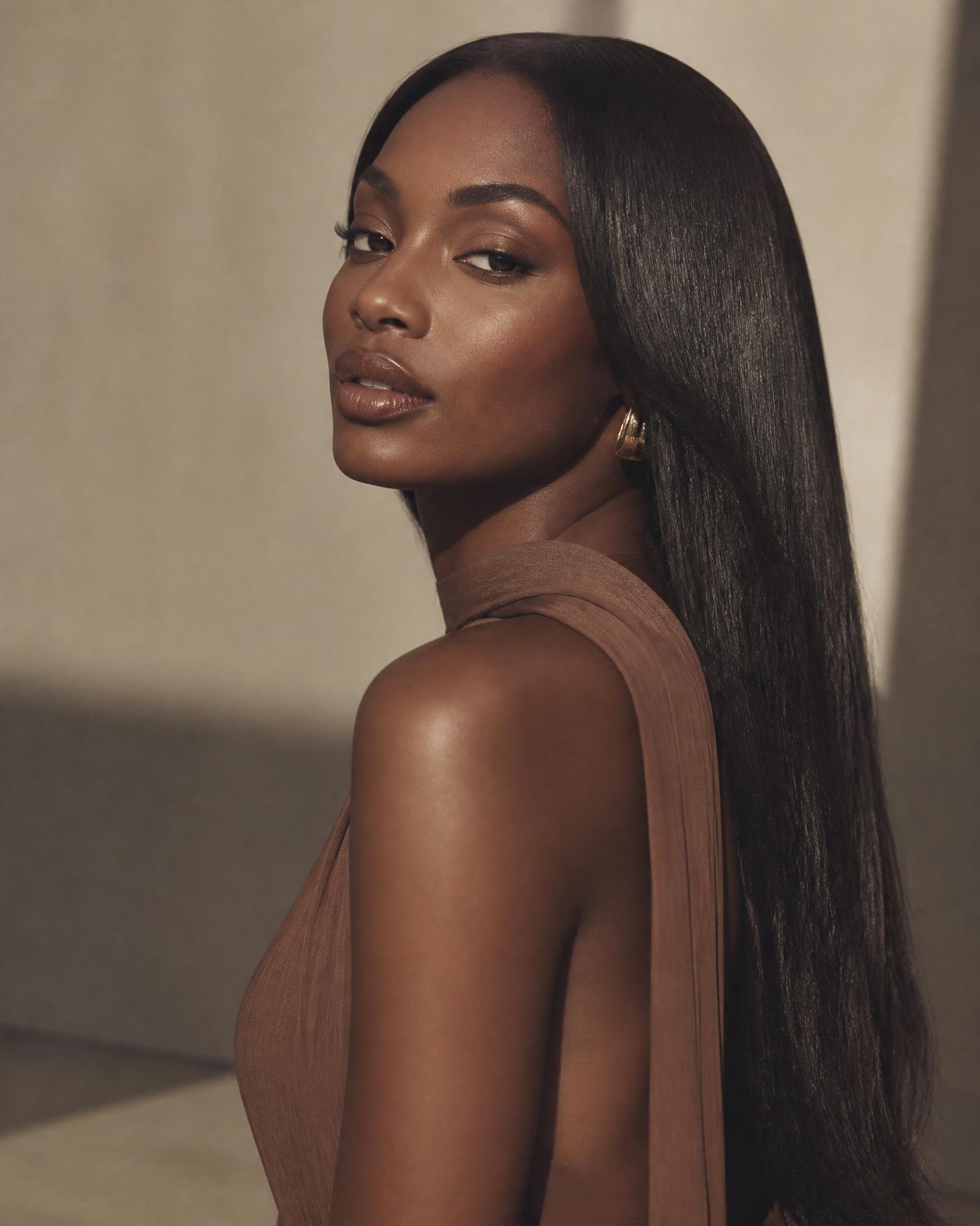 Model wearing a sleek, glossy Neny's Signature Hairs straight wig in warm studio light